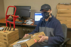 Student unpacking laptops for installation as part of Avivo's IT/Information Technology Career Training Program.