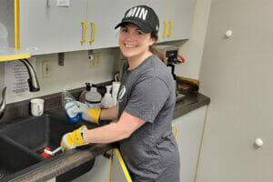 An Avivo volunteer poses as she cleans a kitchen.