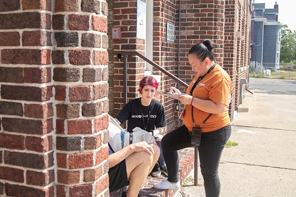 Members of Avivo's Street Outreach Team speak with a person on a staircase.