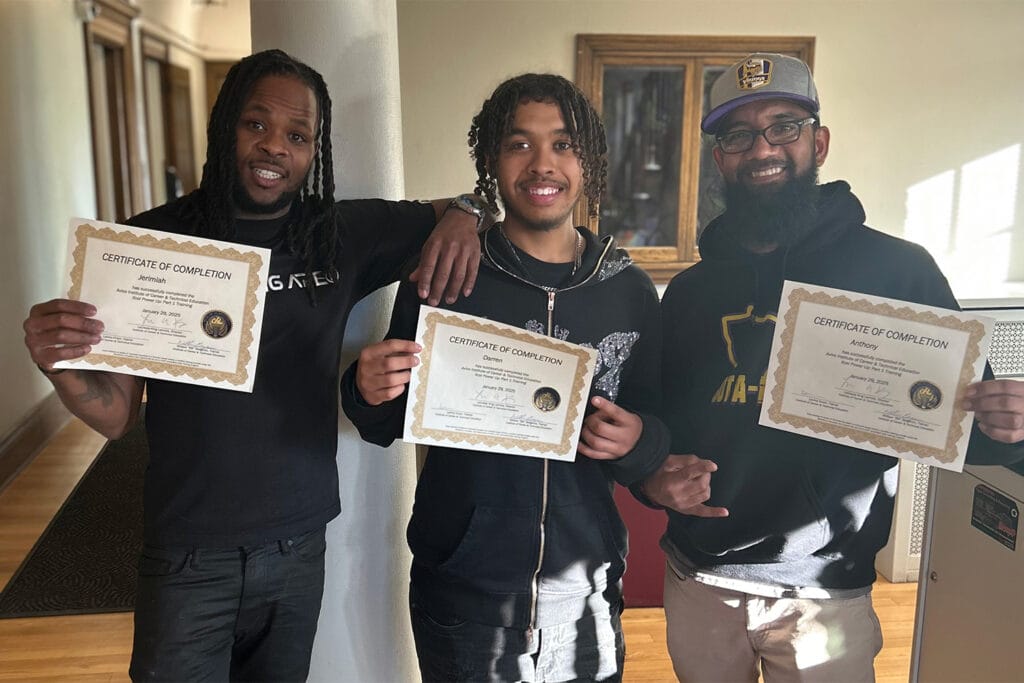 Three people who graduated from a training course pose for a group photo.